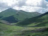 07 Road Between Babusar Pass And Lake Lulusar In Kaghan Vallery Over the Babusar Pass there is a barren green valley with patches of snow still clinging to the black mountain tops.